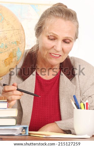 An older teacher looks frustrated over some papers and books