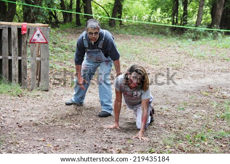 MUSKOGEE, OK - Sept. 13: A very flexible actor terrifies athletes as a bloody zombie during the Castle Zombie Run at the Castle of Muskogee in Muskogee, OK on September 13, 2014.