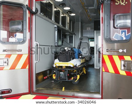 Paramedic\'s truck with open back doors, where stretcher and medical equipment is visible. All trademarks, names and identifications removed.
