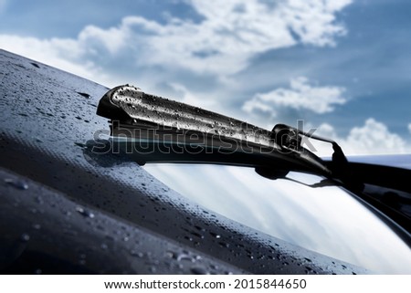 Closeup of wet windshield wiper, wipping windscreen outside
