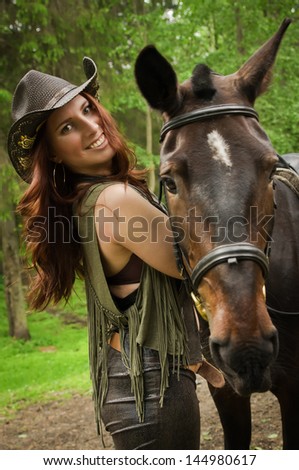 Young cowgirl with brown horse in the forest