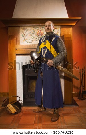 Medieval knight with sword against fireplace