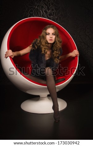 Attractive woman in sexy lingerie sitting in a red ball-chair