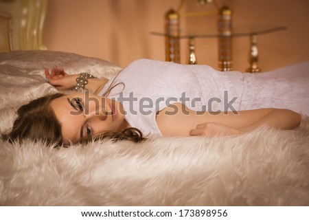 Elegant girl in evening dress posing in an elegant bedroom