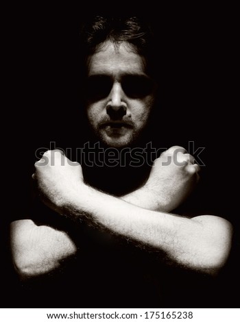 Strong man with arms crossed on black background