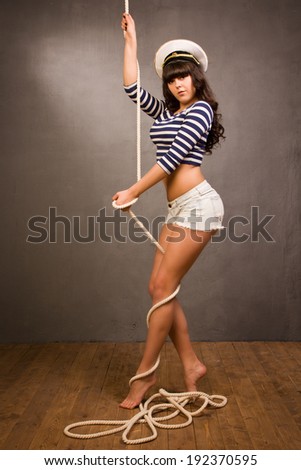 Beautiful navy pinup girl wearing striped sailor top and admirals hat with rope