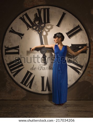 Woman in a long blue dress on the background of a large clock face