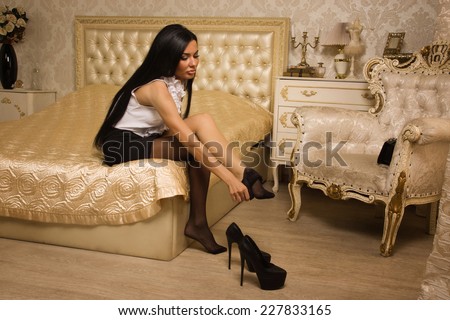 Sensual brunette woman in high heels take off black stockings