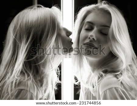 Mirrored shot of a gorgeous young blond kissing herself