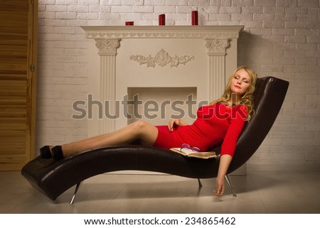 Beautiful lady in a red dress sleeping on the couch  in the vintage interior