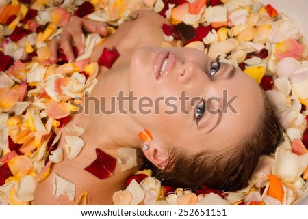 Beautiful sexy woman in bath with flowers petals. Spa body care.