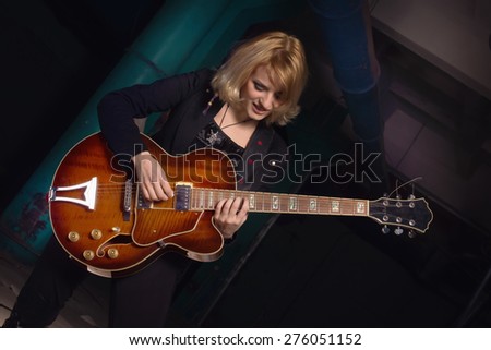 Rock star playing guitar on industrial background. Low key