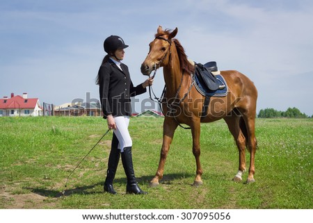 Beautiful young girl jockey talks with her horse dressing uniform competition