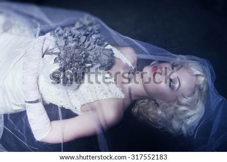 Sleeping Beauty. Beautiful lifeless bride in white dress lying on the shore in a tomb. Dark mystery scene. Low key