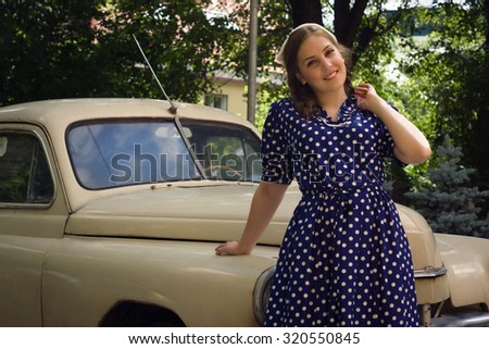 Beautiful lady in vintage dress standing near retro car