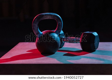 Kettlebell and dumbbell in red-blue gradient light on dark background Photo stock © 