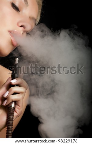 Beautiful woman smoking a hookah and smoke issues from the mouth