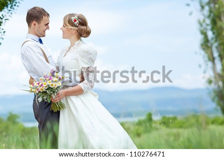 young wedding couple - freshly wed groom and bride posing outdoors on a lovely  day