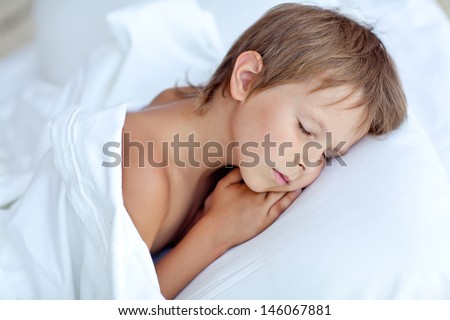Portrait of a baby sleeping on a white pillow and blanket