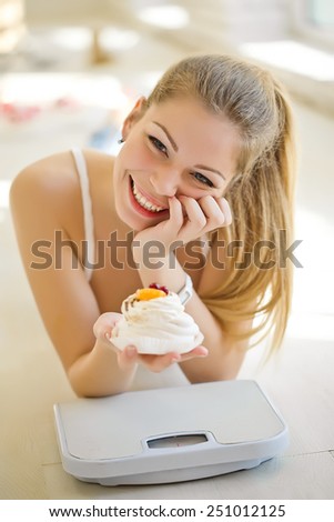 Beautiful slim woman with weights and a dessert