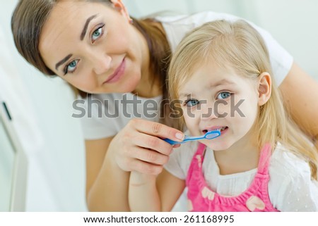 Mother teaching cute baby how to brush teeth with toothbrush