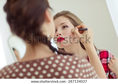 make up artist doing professional make up of young woman