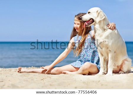 A little girl with a dog by the sea. A child and a dog.