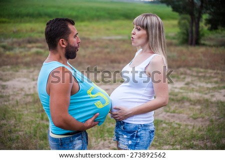 Funny Mom and Dad touch each other with their bellies outdoor