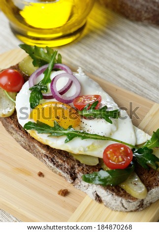 Fried egg and greens open sandwich on the cut board