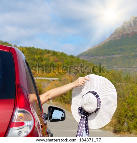 Woman shows sun hat from car window - Travel vacations concept