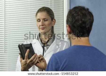 Doctor entering information into tablet while with patient, horizontal