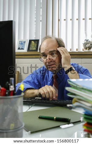 Confused businessman at his desk, vertical
