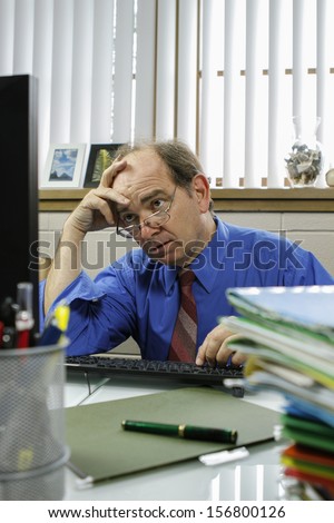 Frustrated businessman at his computer in office, vertical