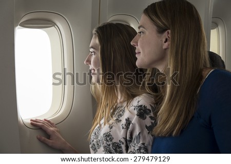 Mother and teen daughter looking out the airplane window