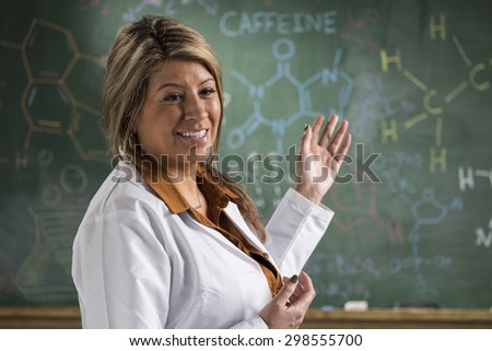 A Chemistry teacher in front of a chalkboard teaching in a classroom setting