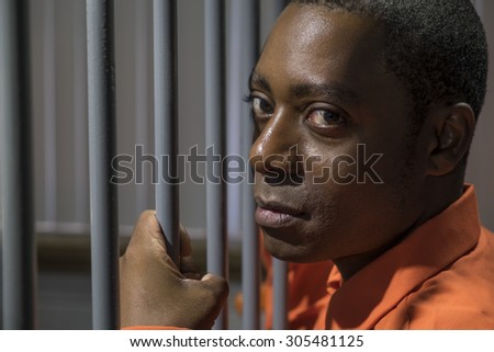 African American male behind bars in a jail cell