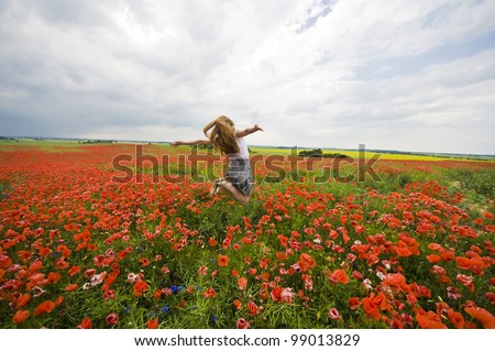 Girl jumping in red poppies field