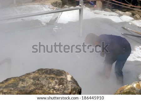 OWAKUDANI, JAPAN - APRIL 2: Local man boils eggs in the sulphurous vapor at April 2, 2014 in Owakudani, Japan. Owakudani is a volcanic area close to the sacred Mt. Fuji. Eggs are boiled in the steam.