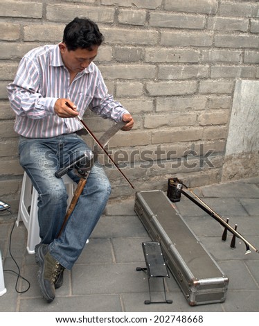 BEIJING, CHINA - JUNE 6: Artist plays music on a saw  on June 6, 2014, Beijing, China. Talented artists are a frequent sight in China, they cover their living costs from public music.