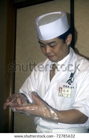 TOKYO - FEBRUARY 24: Japanese cook prepares sushi on a food fair on February 24, 2011 in Tokyo. Sushi is the world famous gem of Japanese cooking.