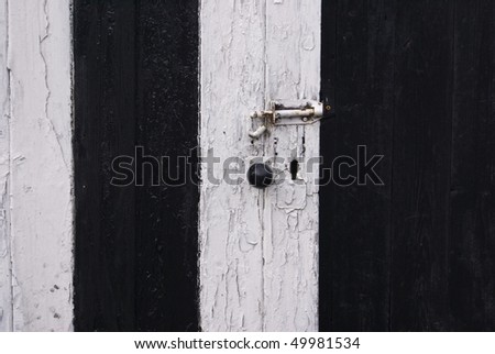 Old decaying black and white striped door with old door furniture and locks