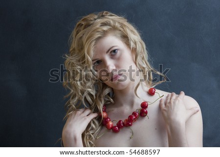Young sexual model. Photographing in studio. Beads from a sweet cherry.