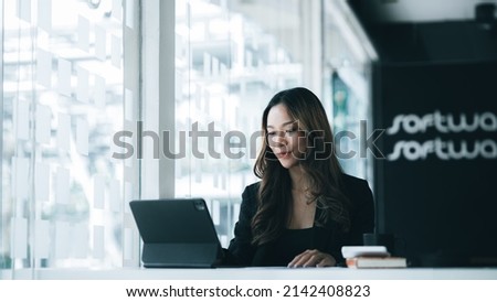 A beautiful Asian businesswoman sitting in her private office, she is checking company financial documents, she is a female executive of a startup company. Concept of financial management. Foto stock © 