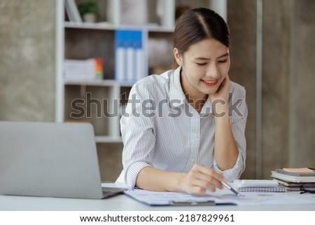 A businesswoman is checking company financial documents and using a laptop to talk to the chief financial officer through a messaging program. Concept of company financial management. Stockfoto © 