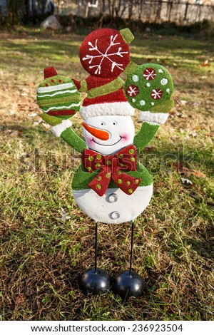 A snowman stands ready to decorate for the holidays