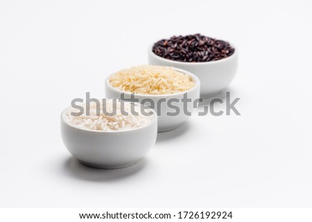 Rice the staple food of the world. 3 varieties of rice, white jasmin, basmati and black rice in white bowls on white background with copy space. Rice is the most consumed staple food ingredient. 商業照片 © 