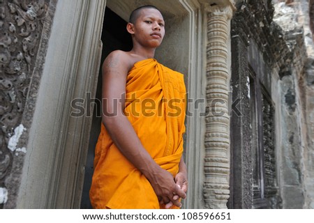 ANGKOR WAT - JULY 11: A Buddhist monk waits for alms on July 11, 2012 in Angkor Wat, Cambodia. There are estimated to be over 50,000 Buddhist monks in Cambodia, with 97% of the population Buddhist.