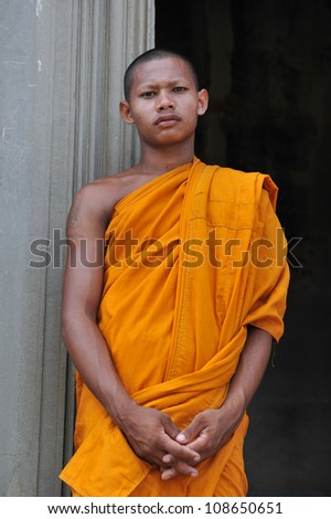 ANGKOR WAT - JULY 11: A Buddhist monk waits for alms on July 11, 2012 in Angkor Wat, Cambodia. There are estimated to be over 50,000 Buddhist monks in Cambodia, with 97% of the population Buddhist.