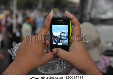 BANGKOK - NOV 24: A protesters uses a smartphone to video an anti-government Pitak Siam rally at Makhawan Bridge on Nov 24, 2012 in Bangkok, Thailand.