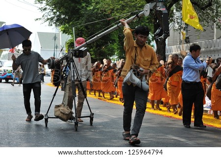 BANGKOK - JAN 25: A film crew use a DSLR mounted on a mobile rig to film monks making a pilgrimage through central Bangkok on Jan 25, 2013 in Bangkok, Thailand.